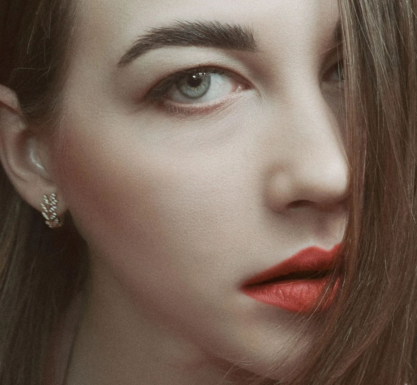 Detailed close-up portrait highlighting woman's red lipstick and expressive eye.